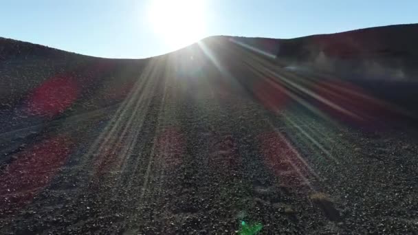 Aerial drone scene following van with caravan at desertic slope discovering sunset with flares and volume light and amazing mountain chains at backgorund. Antofalla, Catamarca, Argentina — Stock Video