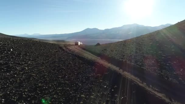 Escena aérea de drones de furgoneta con caravana en pendiente desértica descubriendo la puesta de sol con bengalas y luz de volumen y cadenas montañosas increíbles con amplio valle en backgorund. Antofalla, Catamarca, Argentina — Vídeos de Stock