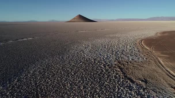 Cena de drones aéreos subindo do chão até a alta visão geral da pirâmide natural solitária em amplo salar marrom ao pôr do sol. Cono de Arita, Salta, Argentina . — Vídeo de Stock