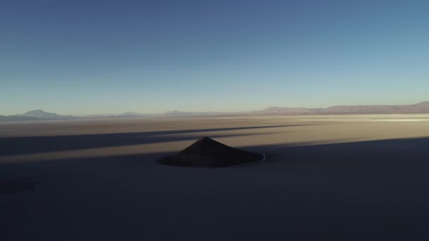 Повітряний загальний вигляд природних ізольованих пітлі в широкому коричневий і білий сальар на заході, конус в тіні. Літаючи назад. Золота година. Абстрактна природа. Коно-де-Аріта, Сальта, Аргентина — стокове відео