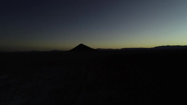Escena aérea de drones de silueta de montañas y pirámides naturales perfectas al amanecer. Volando hacia arriba. Escena negra y naranja. Salar de Arizaro, Cono de arita, Salta, Argentina — Vídeo de stock