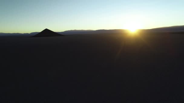 Aerial allmän bild av silhuettfluga av naturliga isolerade pyamid i breda bruna och vita salar vid soluppgången. Solen skapar volym ljus. Flyger i sidled. Gyllene timmen. Abstrakt natur. Cono de Arita, salta — Stockvideo