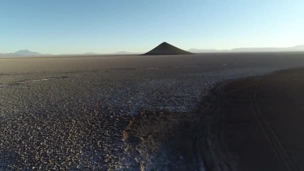Scena lotnicza latające z podłogi w kierunku naturalnej piramidy w białym i Salar, ogólny widok imponujący stożek. Czas wschodu słońca. Długi odcień i kontrast. Cono de Arita, Salta, Argentyna — Wideo stockowe