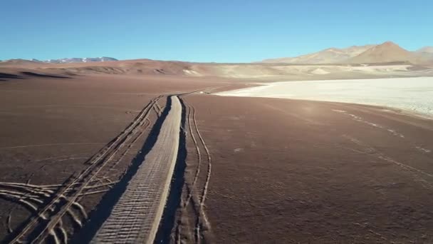 Escena aérea de drones volando towars 4x4 off road van con caravana en límite de salar blanco con montañas desérticas marrones. Formar frente a la vista senital del coche. Salar de Arizaro, Salta, Argentina — Vídeo de stock