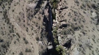 Kuru çöl manzarasıküçük kayalık kanyon içinde nehir boyunca uçan hava senital drone sahne. Rioja Eyaleti'ndeki Hualco Kanyonu, Arjantin