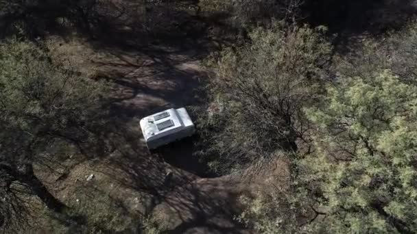 Воздушные сенитальные беспилотники летают над деревьями, показывая детали каравана, автодом, подготовленные для жизни на природе, приключения. Риоха, Аргентина — стоковое видео