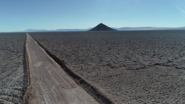 A természetes piramis, az Arita kúp, széles salar a légi még. Kavics off road Track átkelés táj. Hegyláncok a háttérben. Arizaro salar, Salta, Argentína. — Stock videók