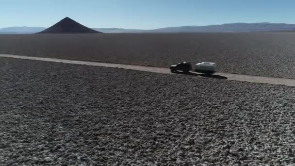 Antena Drone scena po z boku 4x4 z karawaną podróży Off Road na szerokim Salar z naturalnej piramidy w tle. Łańcuchy górskie w tle. Arita stożek, Arizaro Salar, Salta — Wideo stockowe