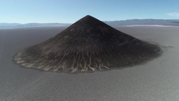 Cena aérea voando sobre pirâmide isolada natural em amplo salar marrom e branco. Da frente à vista senital de Arita cone, Arizaro salar, Salta, Argentina . — Vídeo de Stock