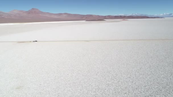 Drohnen-Szene aus der Luft von 4x4 mit Wohnwagen unterwegs entlang der weißen breiten Salar mit. von der allgemeinen Ansicht bis zum Detail des Autos über die Off-Road-Strecke. arizaro salar, salta, argentinien — Stockvideo