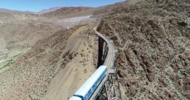Terki dağlık arazide eski metal köprüden geçerken trenin üzerinden hava uçuşu. Demir köprünün genel görünümü. Couds Treni, tren de las nubes, San Antonio de los Cobres