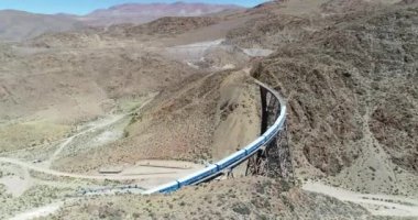 Terki dağlık arazide eski metal köprüden geçerken trenin üzerinden hava uçuşu. Demir köprünün genel görünümü. Couds Treni, tren de las nubes, San Antonio de los Cobres