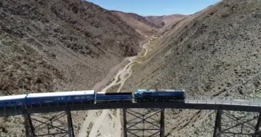 Terk idamı ndaki eski metal köprüden geçen vagon ve lokomotif treninin havadan detayları. Couds Treni, tren de las nubes, San Antonio de los Cobres