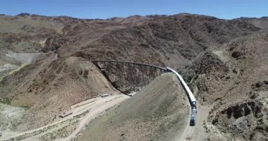 Çölgibi dağlık vadide eski metal köprü üzerinden sürüş tren havadan drone sahne. Demir köprünün genel görünümü. Couds Treni, tren de las nubes, San Antonio de los Cobres