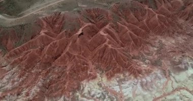 Kırmızı aşınmış kuru dağlık manzaranın yukarıdan ön görünümüne havadan. Kırmızı, turuncu ve beyaz katmanlı renklerle kuru vadiyi keşfetmek. Mars vadisi, Valle de Marte, Cusi Cusi, Jujuy