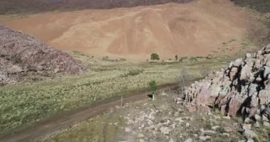 Kayalık mounrainous manzara kumul doğru uçan hava drone sahne. Yeşil vadi ve kuru çölya yamaçları ile kontrast. Abra Pampa, Jujuy, Argetina. Huancar kumulları