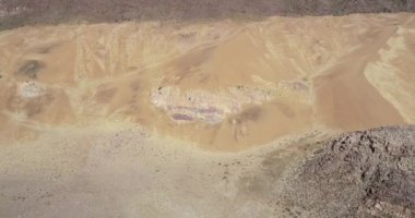 Kayalık dağlık arazide uzanarak kum ulanından uçarak uzaklaşan hava drone sahnesi. Meandrik nehir ile yeşil vadi ile arazi formunun genel görünümünü keşfetmek. Abra Pampa, Jujuy, Argetina. Huancar kumulları