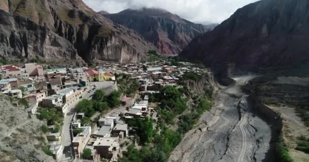 Aerial flying over Iruya, hidden town, at steep narrow valley surrounded of woods and dry colorful hills at background. Touristic town at Salta, Argentina — Stock Video