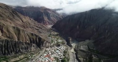 Bulutların, ormanların ve arka planda kuru renkli tepelerin çevrelenmiş dik dar vadisinde, gizli kasaba, Iruya üzerinde uçan hava. Touristic town at Salta, Arjantin