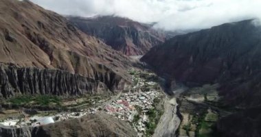 Bulutların, ormanların ve arka planda kuru renkli tepelerin çevrelenmiş dik dar vadisinde, gizli kasaba, Iruya üzerinde uçan hava. Touristic town at Salta, Arjantin