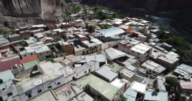 Bulutların, ormanların ve arka planda kuru renkli tepelerin çevrelenmiş dik dar vadisinde, gizli kasaba, Iruya üzerinde uçan hava. Touristic town at Salta, Arjantin