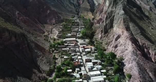 Vuelo aéreo sobre Iruya, ciudad escondida, en el valle estrecho empinado rodeado de nubes, bosques y colinas de colores secos en el fondo. Población turística de Salta, Argentina — Vídeos de Stock