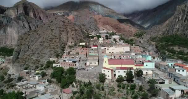 Voando em direção a igreja velha amarela na cidade colocada em encosta íngreme em paisagem colorida seca. Iruya, Salta, Argentina — Vídeo de Stock