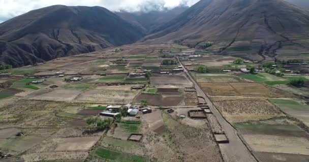 Vuelo aéreo por encima de pequeñas granjas con cultivos en laderas montañosas que descubren un alto acantilado profundo. Antiguo sistema tradicional de cultivo. Pueblo Viejo, Salta, Argentina — Vídeos de Stock