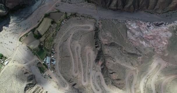 Obere Luftaufnahme einer Schotterstraße mit Serpentinenform am steilen Berghang, die im Tal entlangfliegt. iruya, salta, argentinien — Stockvideo