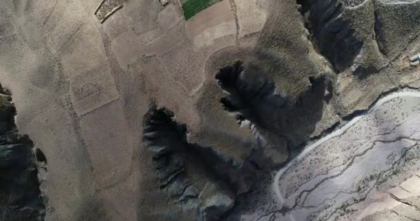 Escena aérea superior de profundo valle estrecho del río descubriendo profundos acantilados y cultivos que cuelgan de las laderas de las montañas. Pueblo viejo, Salta, Argentina . — Vídeo de stock