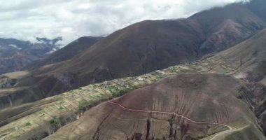 Dağ platosundaki kayalıklardan sarkılan yerel tarımdan doğal şebekenin havadan insansız hava aracı sahnesi. Yamaçta ki serpantin çakıl yolunu keşfetmek. Derin vadiler. Salta, Pueblo Viejo, Arjantin