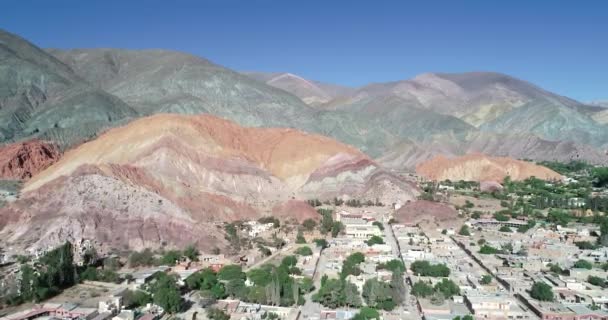 Scena aerea drone ascendente mostrando vista panoramica del villaggio circondato da montagne colorate erose. Seven colors mountains, Purmamarca town, Jujuy, Argentina. Città turistica. Cerro sei coloranti — Video Stock