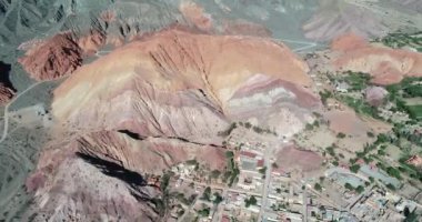 Renkli kuru dağlara doğru seyahat hava drone sahne kumtaşı detay gösterir, köy de genel görünümü. Yedi renk dağlar, Purmamarca kasaba, Jujuy, Arjantin. Turistik şehir