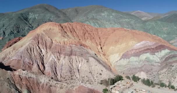 Scène de drone aérien montrant des montagnes colorées sèches de sept couleurs, se déplaçant vers l'arrière à la découverte du village Purmamarca dans la province de Jujuy, en Argentine. Ville touristique — Video