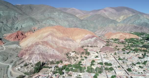 Aerial Drone scen flyttar bakåt visar panoramautsikt över byn omgiven av Colorfull torra berg. Sju färger berg, Purmamarca staden Jujuy, Argentina. Turistiska staden. Cerro Siete Colores — Stockvideo