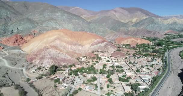 向后移动的无人机场景显示了村庄周围充满色彩干燥的山脉的全景。七色山，普玛马卡镇朱朱伊，阿根廷。旅游城市。塞罗西特颜色 — 图库视频影像