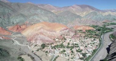 Hava drone sahne renkli dolu aşınmış dağlarla çevrili köyün panoramik manzarasını gösteren yükseliyor. Yedi renk dağlar, Purmamarca kasaba, Jujuy, Arjantin. Turistik bir şehir. Cerro siete renk