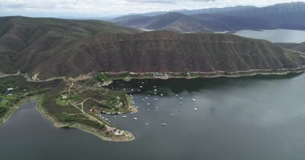 Cena de drone aéreo de visão geral de lago em paisagem montanhosa. Barcos de turistica e iates em bóias de charneca. Cabra Corral Dam, zona turística de Salta, Argentina — Vídeo de Stock