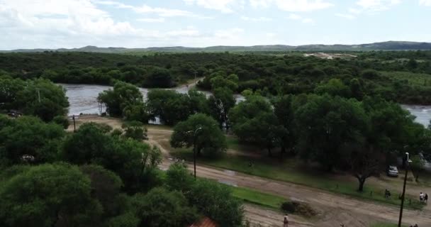 Scena dronów lotniczych z brązową, silną rzeką przelatującą przez most. Powódź w Mina clavero. Rosnąca rzeka nad ulicami miasta. Wznosząc się i lecąc w kierunku i nad wodą. Kordoba, Argentyna — Wideo stockowe