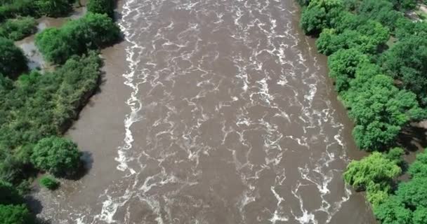 Senital aerial drone scene of brown forest turbulent river with foam drawings over surface. Flying fowards over water. Polluted waters. Cordoba, Argentina — Stock Video