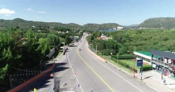 Cena aérea de drone de cidade turística ao lado de lago com hotéis em ambientes em paisagem montanhosa. Represa com atrações turísticas. Potrero de los Funes, San Luis, Argentina — Vídeo de Stock