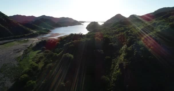 Voyage aérien au-dessus des montagnes forestières sauvages vers le lac au coucher du soleil, heure d'or. L'embouchure du Rio Grande. Lumière de volume. Nogoli, San Luis, Argentine — Video