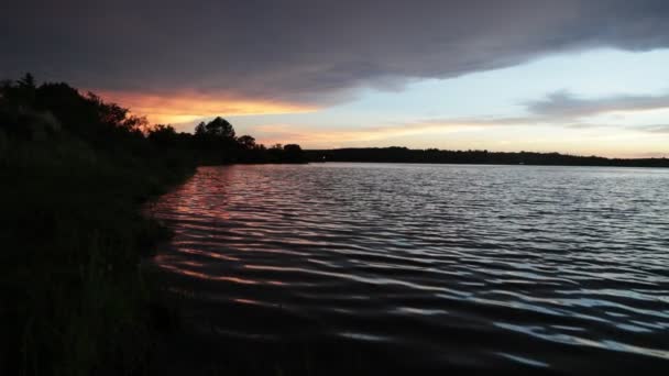 Slow motion of silhouette of coast with movement of water ripples at sunset. Scene of contrast colors movement, black blue golden and silver. Trapiche, San Luis, Argentina — Stockvideo