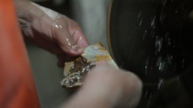 Yarı değerli taşla çalışan bir adamın yavaş çekim görüntüsü. Onix kayalarını kesip disk ve su keserek mücevher oluşturun. La Toma, San Luis, Arjantin