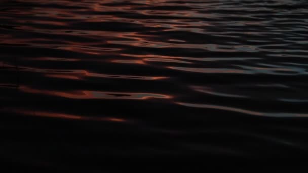 Mouvement lent des ondulations d'eau au coucher du soleil. Scène abstraite de mouvement de couleurs contrastées, noir bleu et argent. Trapiche, San Luis, Argentine — Video