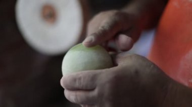 Yarı değerli yeşil küre gösteren bir adamın yavaş çekim sahnesi. Eller yukarı, arka planda beyaz disk dönüyor. El işi dekorasyonu. La Toma, San Luis, Arjantin