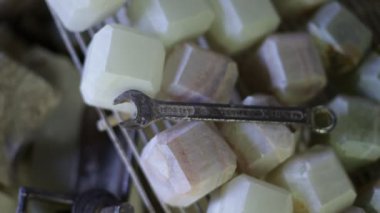 Onix, yarı değerli kübik taşlar, beyaz, yeşil ve sarı. Mücevher el sanatları için hazır. Kayaların üstünde İngiliz anahtarı. La Toma, San Luis, Arjantin