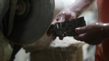 Yarı değerli taşla çalışan bir adamın yavaş çekim görüntüsü. Stromatolit kaya fosilini kesip disk ve su keserek mücevher yaratmak için ellerinizi kapatın. La Toma, San Luis, Arjantin
