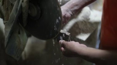Yarı değerli taşla çalışan bir adamın yavaş çekim görüntüsü. Stromatolit kaya fosilini kesip disk ve su keserek mücevher yaratmak için ellerinizi kapatın. La Toma, San Luis, Arjantin