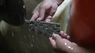 Yarı değerli taşla çalışan bir adamın yavaş çekim görüntüsü. Stromatolit kaya fosilini kesip disk ve su keserek mücevher yaratmak için ellerinizi kapatın. La Toma, San Luis, Arjantin